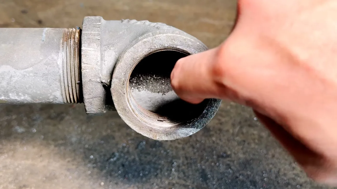 Fingertip inside the open end of a threaded cast iron pipe fitting
