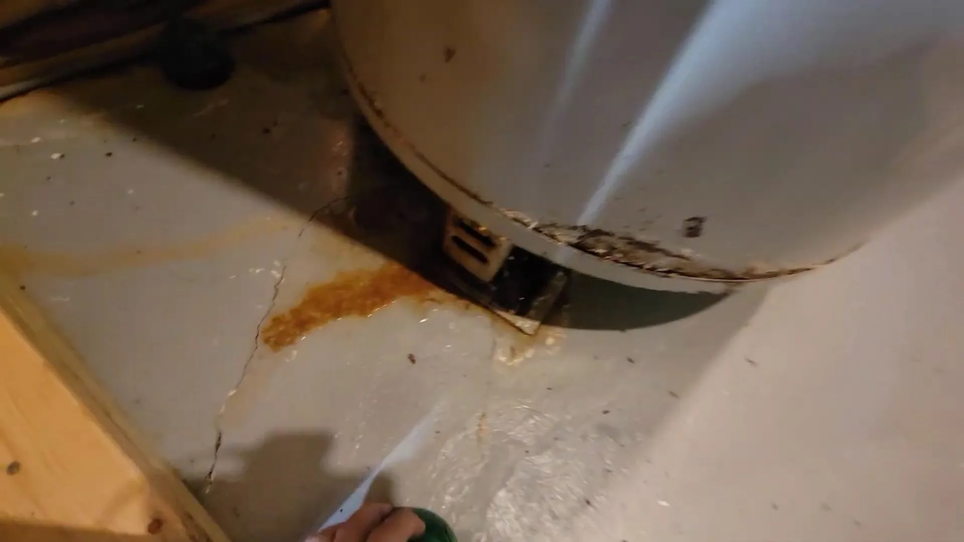 Rust-colored stain on the floor around the base of a white water heater tank