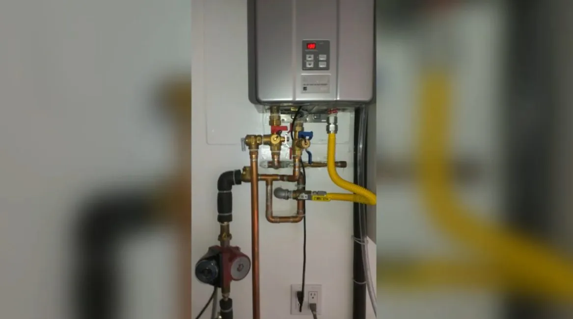Wall-mounted tankless water heater with copper lines, valves and a yellow gas line beneath it